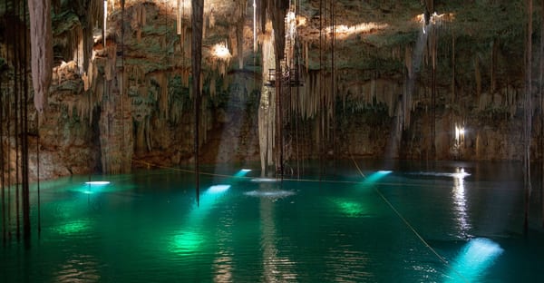 Location Turquoise water inside a limestone cenote, with stalactites hanging from the cave roof