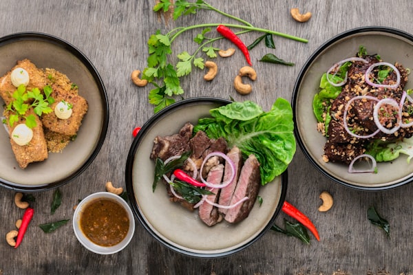 Location Three plated dishes seen from above on a wooden table