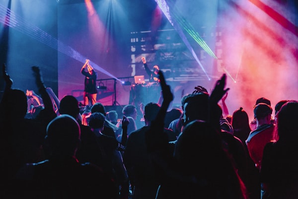 Location A crowd with raised hands in front of a stage lit in colour