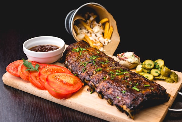 Location Wooden board with grilled ribs, sliced tomato and fries