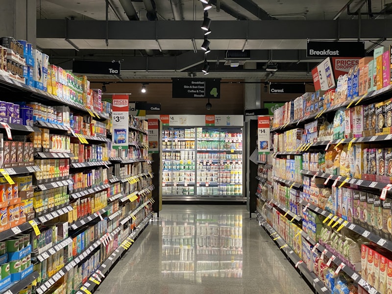 Location Supermarket aisle with shelves on both sides and a chiller at the far end