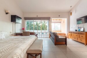 Spaces Large bedroom with a bench at the foot of the bed, a sofa, a TV and a garden window