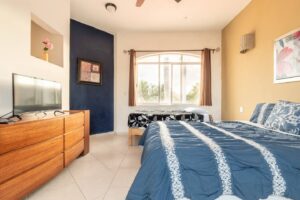 Spaces Bedroom with a blue accent wall, two beds, a long wooden dresser and a TV