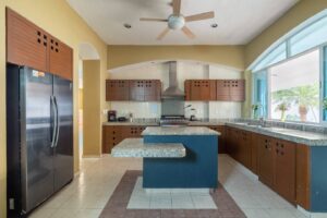 Spaces Kitchen with a stainless steel fridge, a central island, extractor hood and granite counters