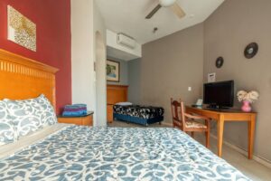 Spaces Bedroom with a red accent wall, a wooden headboard and a desk with a TV