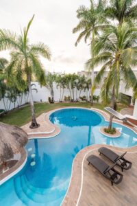 Spaces The pool curving around a palm tree, with sun loungers on the deck