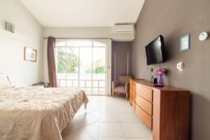 Spaces Bedroom with a dresser, a wall TV and a tall window opening onto the terrace