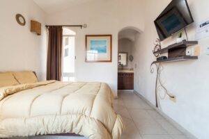 Spaces Bedroom with a wall TV, a curtained window and an arch through to the bathroom