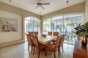 Spaces Dining room with a long table for eight and arched windows facing the pool