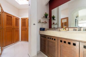 Spaces Bathroom vanity with a double sink, a large mirror and louvered wooden closet doors