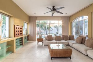 Spaces Long living room with a sectional sofa, built-in shelving and windows onto the pool
