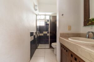 Spaces Narrow bathroom with a chequered tile shower and a stone vanity