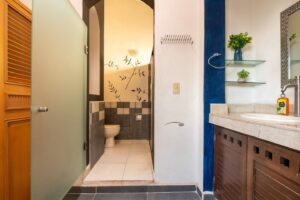 Spaces Bathroom with a blue accent wall, a stone vanity and the toilet behind a partition