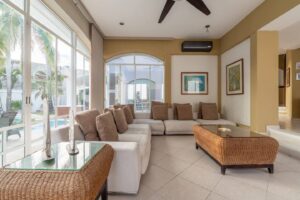 Spaces Living room with a sectional sofa and wicker tables, open to the pool