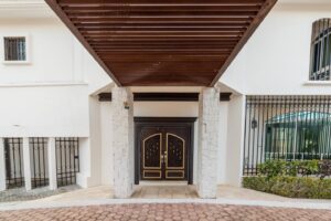 Spaces The main entrance: a dark wooden double door under a slatted wood canopy