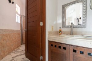 Spaces Bathroom with a walk-in shower, a wooden door and a stone vanity with a framed mirror