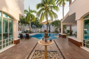 Spaces Inner courtyard with a stone fountain and a palm tree, with the pool behind it