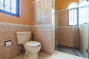 Spaces Bathroom with a tiled toilet area and a glass shower under an arched window