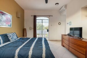 Spaces Bedroom with a blue bedspread, a dresser with a TV and a door to the terrace